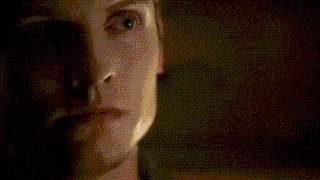 a close up of a woman 's face with a candle in the background