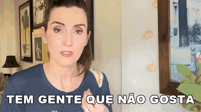 a woman in a blue shirt says tem gente que nao gosta in a room