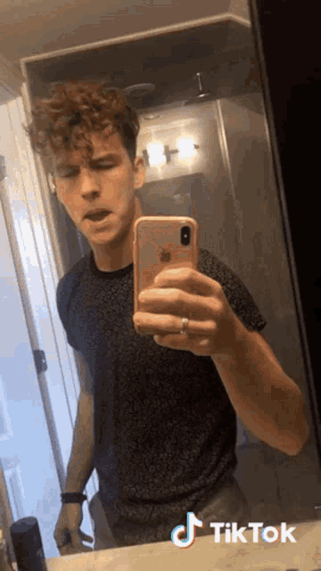a young man is taking a selfie in front of a mirror with tiktok written on the bottom right