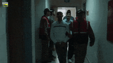 a group of men are walking down a hallway with a yellow sign that says getto libo