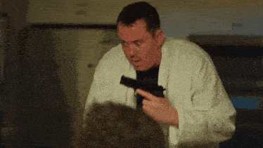 a man in a white robe is holding a black gun
