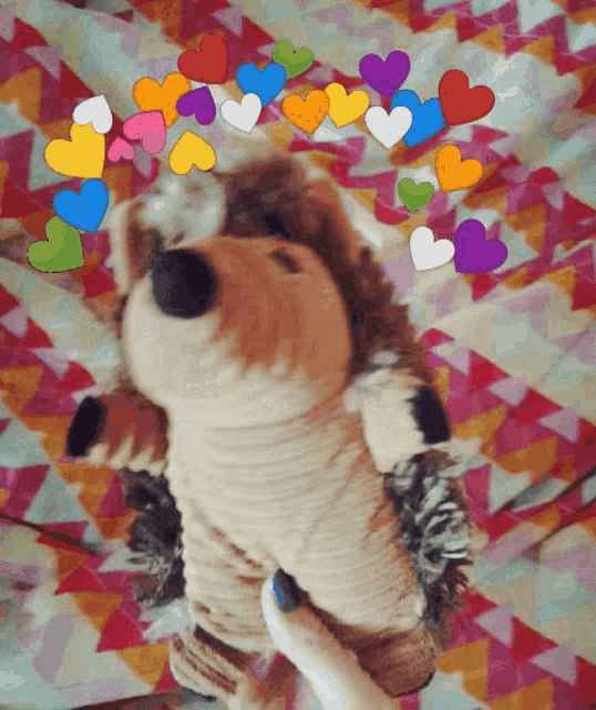 a stuffed hedgehog laying on a bed with hearts around it