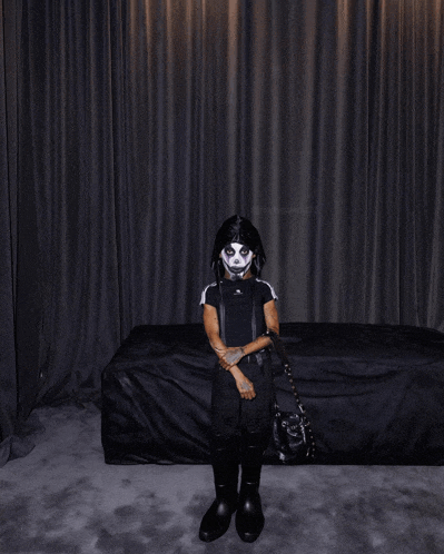 a person in a skeleton costume is standing in front of a dark curtain