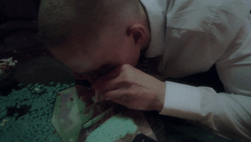 a man in a white shirt is laying on the floor with a bag of pills in front of him