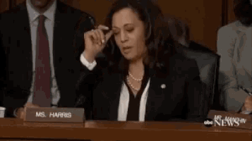 a woman sits at a table with a name plate that says ms. harris