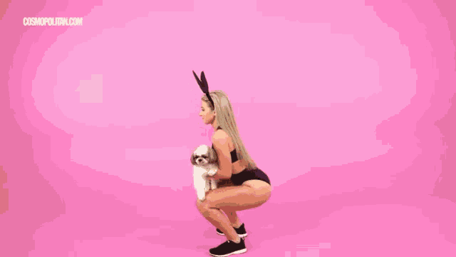 a woman in bunny ears squatting with a dog