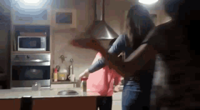 a group of people are dancing in a kitchen with a microwave in the background .