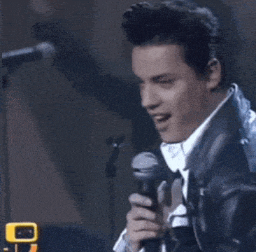 a man in a leather jacket singing into a microphone .