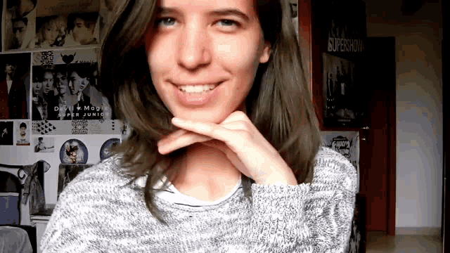 a girl is smiling in front of a wall that has a poster that says supershow on it