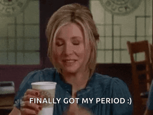 a woman covering her face with her hand while holding a cup of coffee and saying finally got my period .