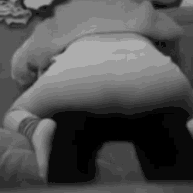 a black and white photo of a person kneeling on a bed .