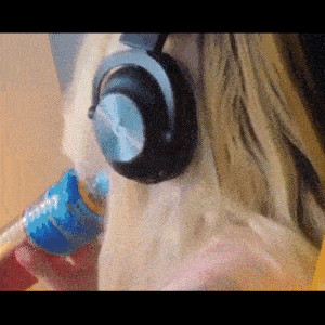 a woman wearing headphones holds a can of soda