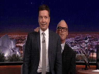 a man in a suit and tie is standing next to another man in a suit .