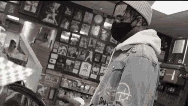 a man wearing a mask is standing in front of a wall with pictures and a sign that says ny on it