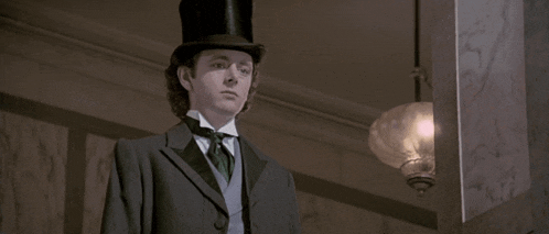 a man in a top hat and suit stands next to a lamp