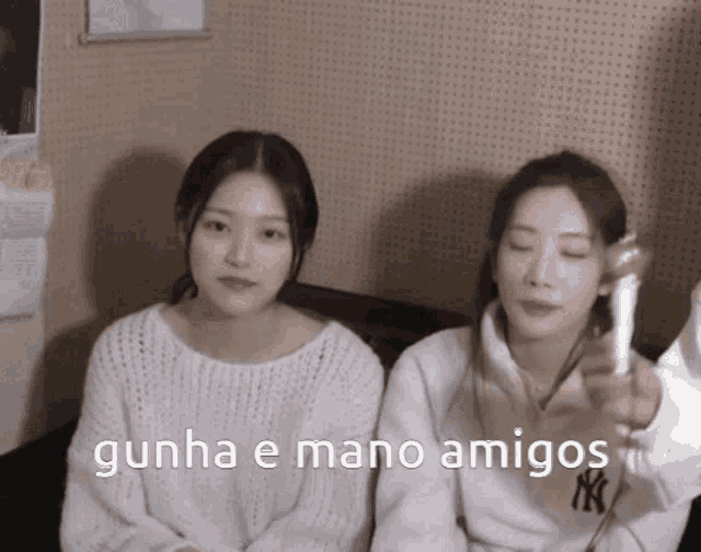 two girls are sitting next to each other with the words gunha e mano amigos on the bottom right