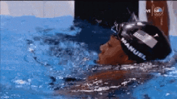 a man is swimming in a pool with manuel on his headband .