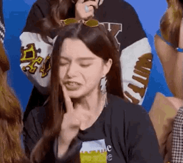a woman is making a funny face with her finger in her mouth while standing in front of a group of people .