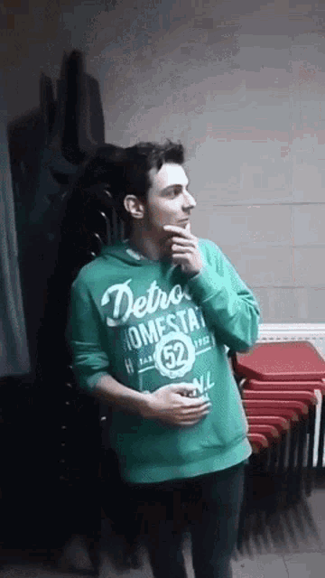 a man wearing a green sweatshirt that says detroit homestead