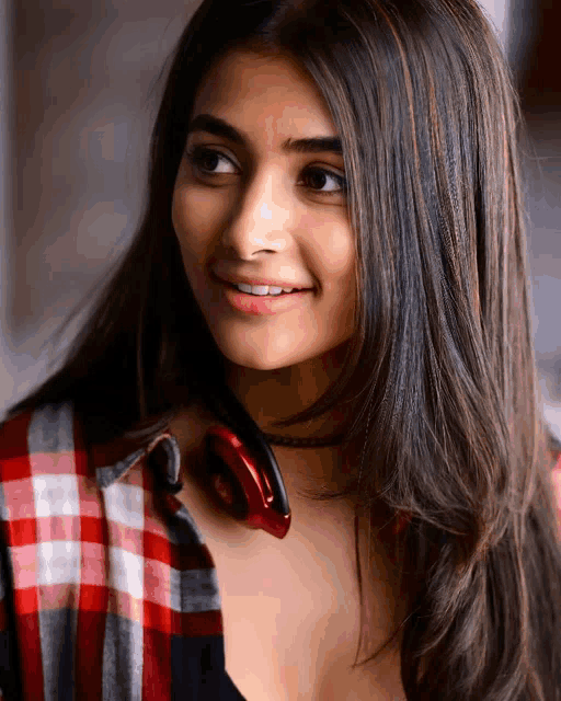 a woman wearing headphones and a plaid shirt smiles for the camera