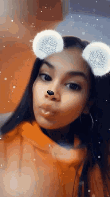 a girl wearing a hoodie and earrings is taking a selfie with snowflakes on her ears .