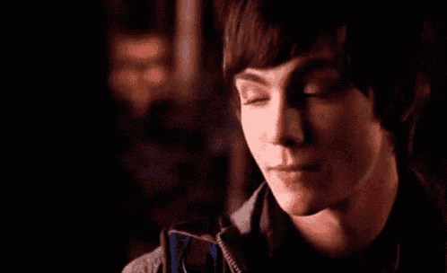 a close up of a young man 's face in a dark room looking at the camera .
