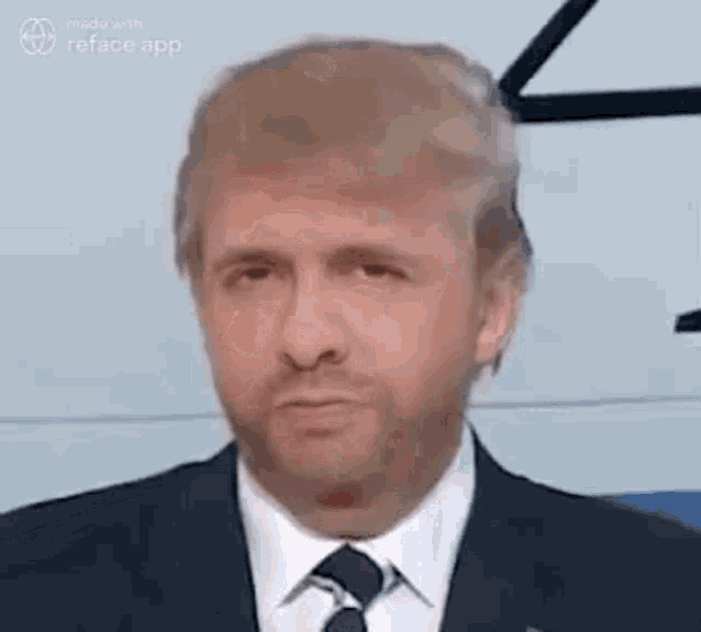a man in a suit and tie is looking at the camera with a serious look on his face .
