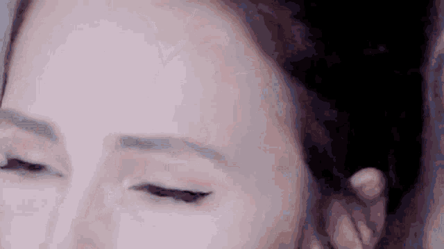 a close up of a woman 's face with her eyes closed and her ear visible