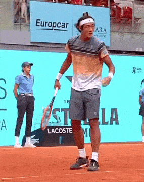a man holding a tennis racquet on a court with a europcar sign behind him
