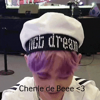 a person with purple hair is wearing a white hat with the word dragon on it .