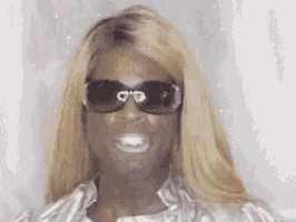 a close up of a woman wearing sunglasses and a silver shirt .