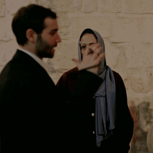 a man and a woman are standing next to each other and the woman is wearing a hijab