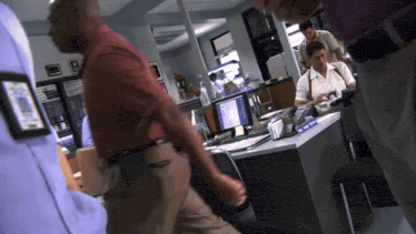 a man in a red shirt walks past a desk with a name tag that says ' sgt. scott '