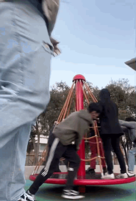 a group of people are playing on a merry go round at a park