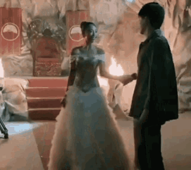 a man and a woman are standing next to each other in a room holding hands .