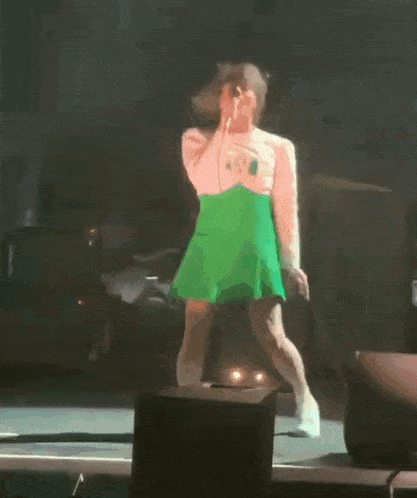 a person in a green dress is dancing on stage