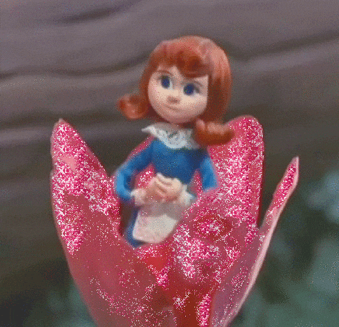 a doll is sitting on a pink flower with glitter on it