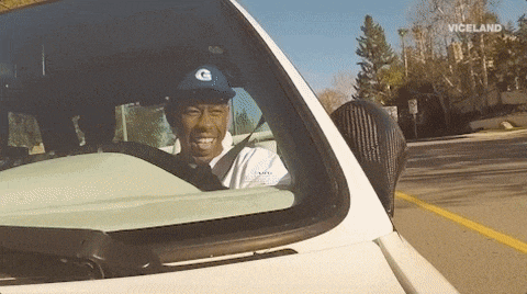 a man wearing a g hat is driving a car