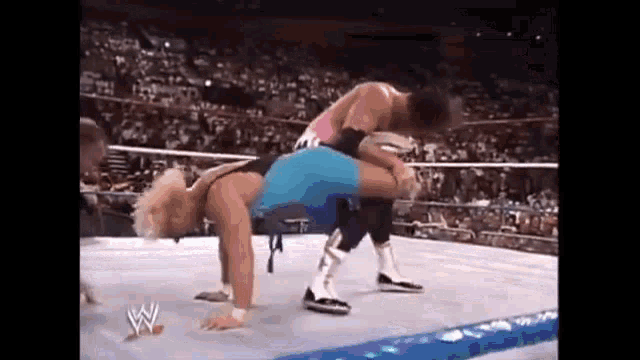 two men are wrestling in a wrestling ring and one of them is doing a handstand .