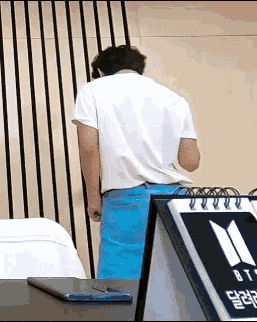a man in a white shirt stands in front of a calendar that says bts