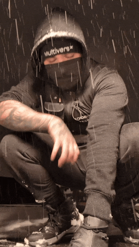 a man wearing a multiverse hoodie is squatting down