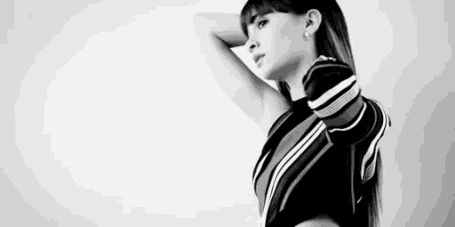 a black and white photo of a woman in a striped shirt with her hand on her head .