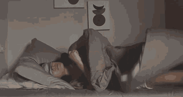 a woman is laying in bed wearing a sleep mask and holding her stomach .