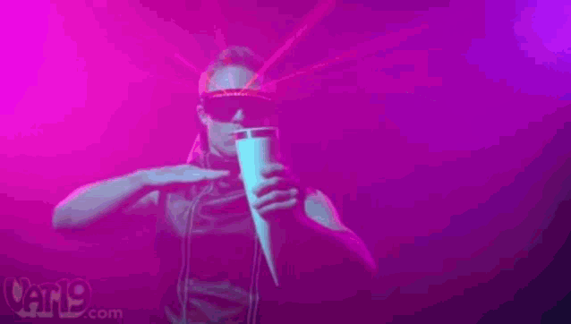 a man wearing sunglasses is singing into a microphone in a dark room ..