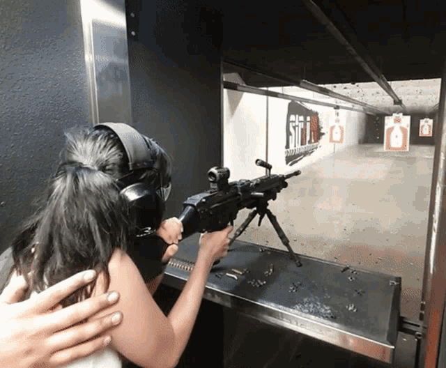 a woman is holding a gun in a shooting range with a sign on the wall that says still