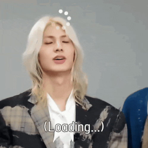 a man with long blonde hair says loading on his face