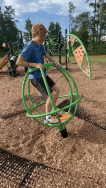 a boy in a blue shirt is playing on a green spinner