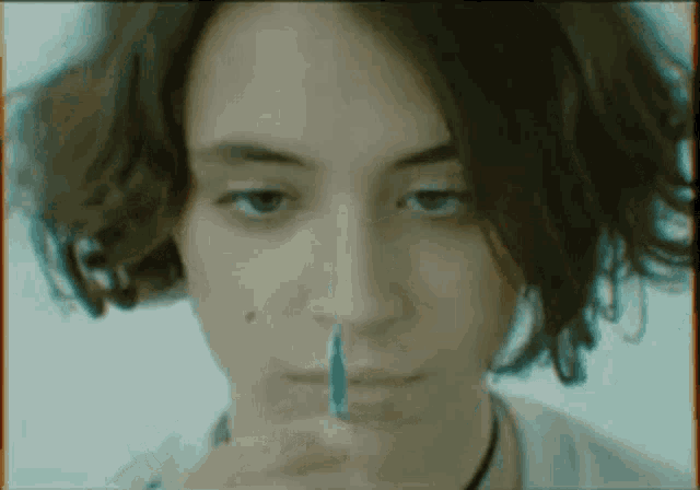 a close up of a woman 's face with a pen in her mouth .