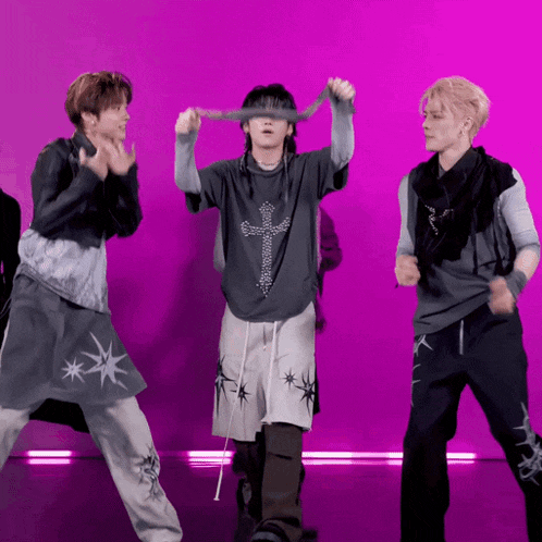 three men are dancing in front of a pink background