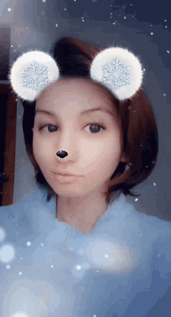 a girl with snowflakes on her ears is wearing a blue shirt